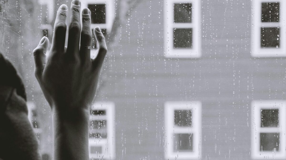 Una persona mira por la ventana con tristeza