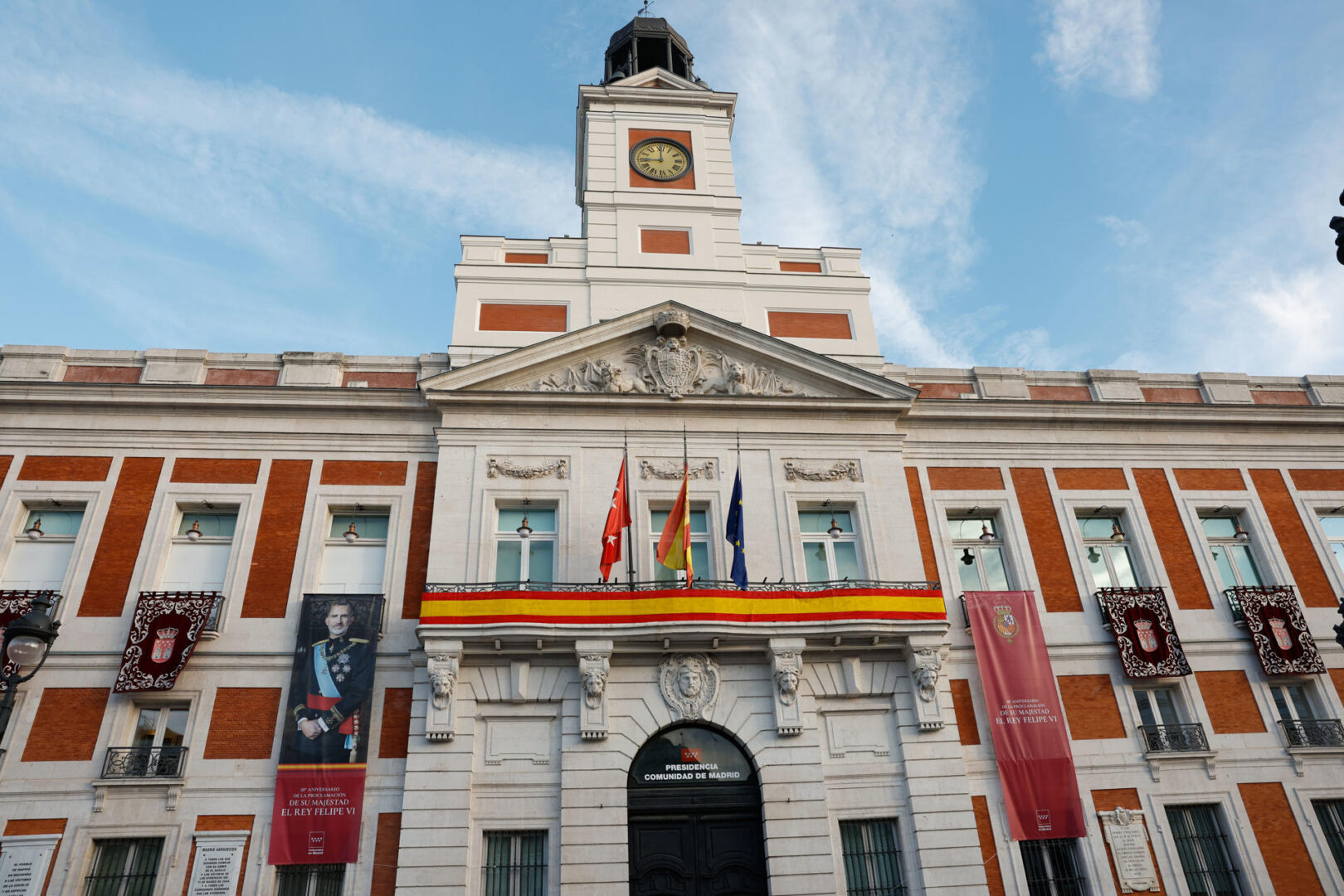 Vista de la sede de la Comunidad de Madrid, en la Puerta del Sol, engalanada con motivo del décimo aniversario de la coronación de Felipe VI.