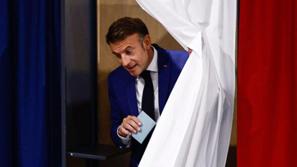 El presidente francés Emmanuel Macron deja una cabina de votación en una mesa electoral durante la primera ronda de las elecciones parlamentarias francesas anticipadas.