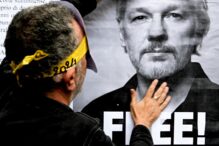 Un activista de la red FreeAssangeNapoli coloca un cartel en un quiosco de prensa abandonado con el anuncio de la liberación de Julian Assange de la prisión.