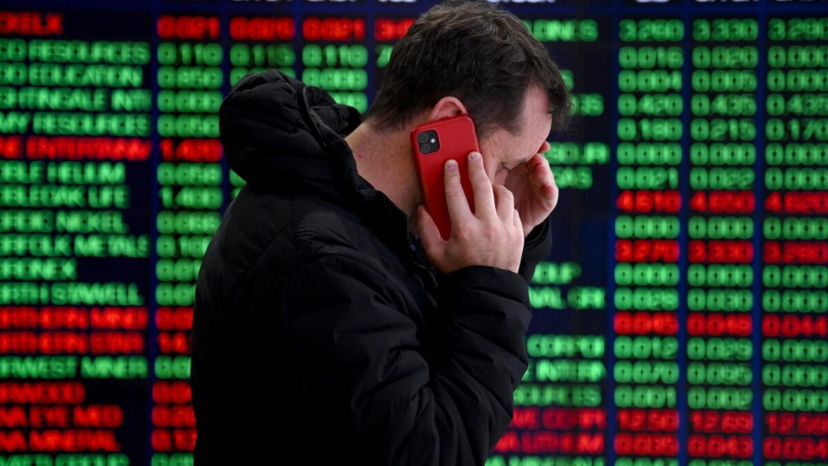 Una persona habla por teléfono frente a los paneles indicadores en la Bolsa de Valores de Australia.