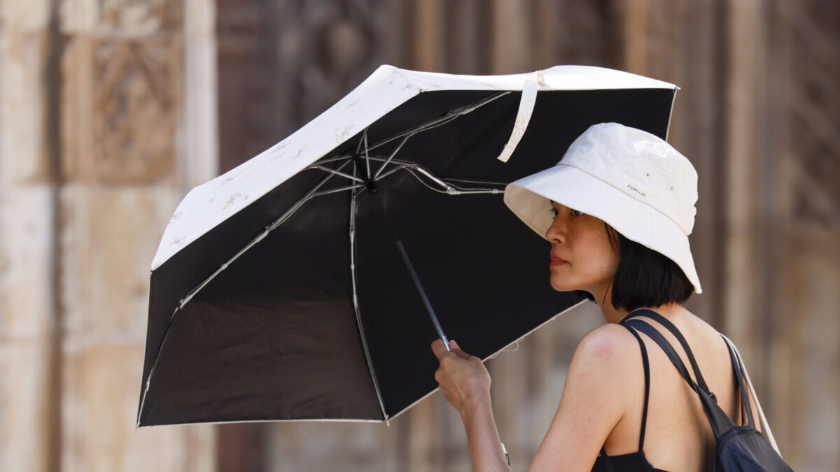 Una turista se protege del calor con parasol.
