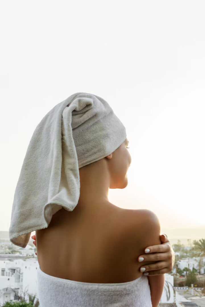 Una mujer con una toalla en la cabeza, tratando de secarse el cabello