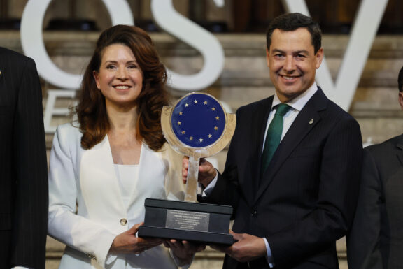 CUACOS DE YUSTE (CÁCERES) (ESPAÑA), 25/05/2026.- La presidenta del Comité Europeo de las Regiones (CDR), Kata Tütto (i) sostiene el Premio Carlos V al Comité de las Regiones de la UE junto a al presidente en funciones de la Junta de Andalucía, Juanma Moreno (d) durante el acto de entrega del XIX Premio Europeo Carlos V celebrado este lunes en el Monasterio de San Jerónimo de Yuste (Cáceres). EFE/ Ballesteros