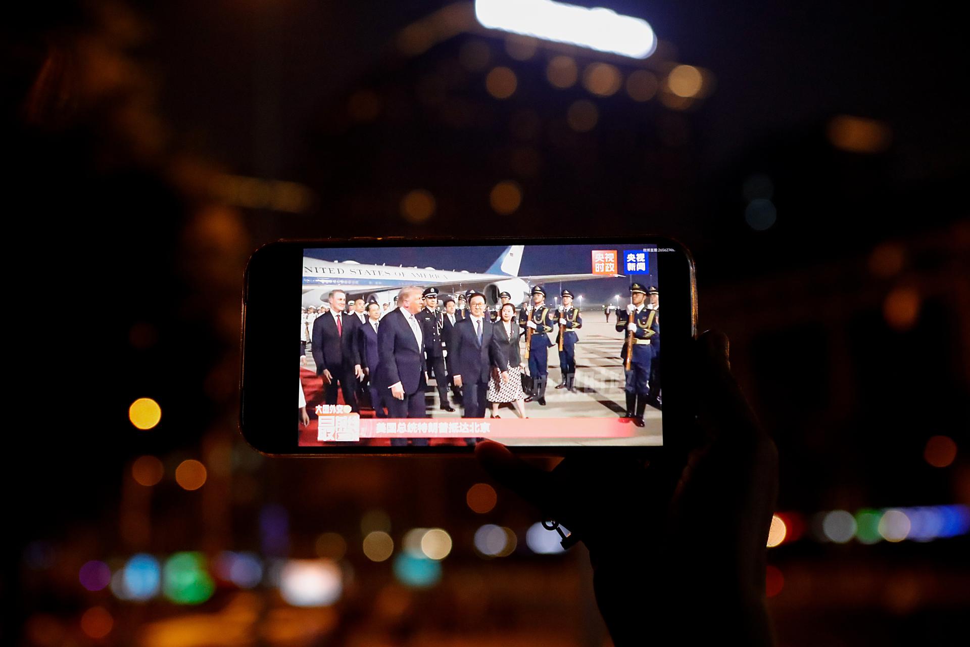 BEIJING (China), 13/05/2026.- A person watches on a smartphone the arrival of US President Donald Trump at the Beijing Capital International Airport, in Beijing, China, 13 May 2026. US President Trump arrived in Beijing for a high-stakes state visit running through 15 May, marking his first return to the mainland since 2017. EFE/EPA/ANNA BAILU