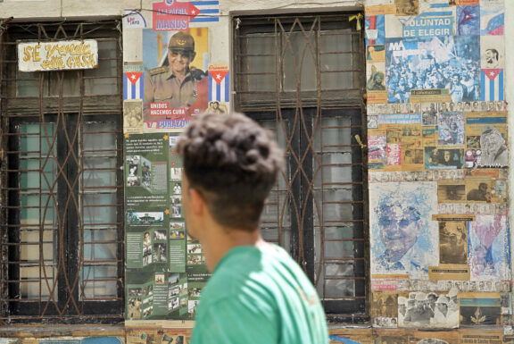 AME3435. LA HABANA (CUBA), 20/05/2026.- Una persona camina frente a una casa con carteles y propaganda política en su fachada este miércoles, en la Habana (Cuba). El Departamento de Justicia (DOJ) de Estados Unidos presentó una acusación criminal contra el expresidente cubano Raúl Castro por la muerte de cuatro aviadores de la organización Hermanos al Rescate hace 30 años, lo que eleva la presión contra La Habana. EFE/ Ernesto Mastrascusa
