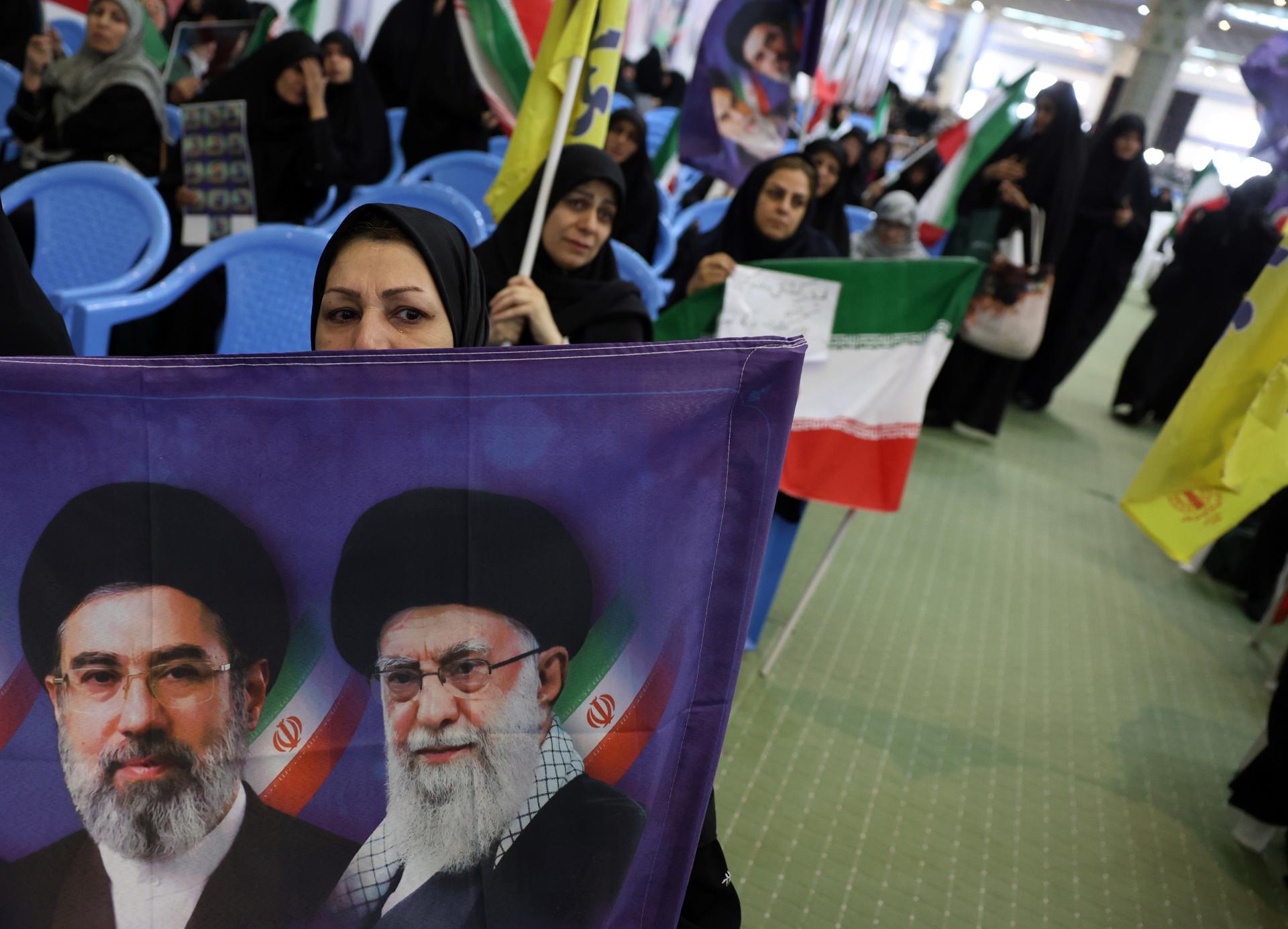 TEHRAN (IRAN(Islamic Republic Of)), 24/05/2026.- Iranian women hold portraits of Irans supreme leader and Iranian national flags during a memorial ceremony for those killed in the Iran-US-Israel war at Mosallah Mosque in Tehran, Iran, 24 May 2026. The ceremony takes place amid diplomatic efforts, with US President Trump announcing that a potential peace agreement to end the conflict and reopen the Strait of Hormuz has been largely negotiated through Pakistani mediators. (Teherán) EFE/EPA/ABEDIN TAHERKENAREH