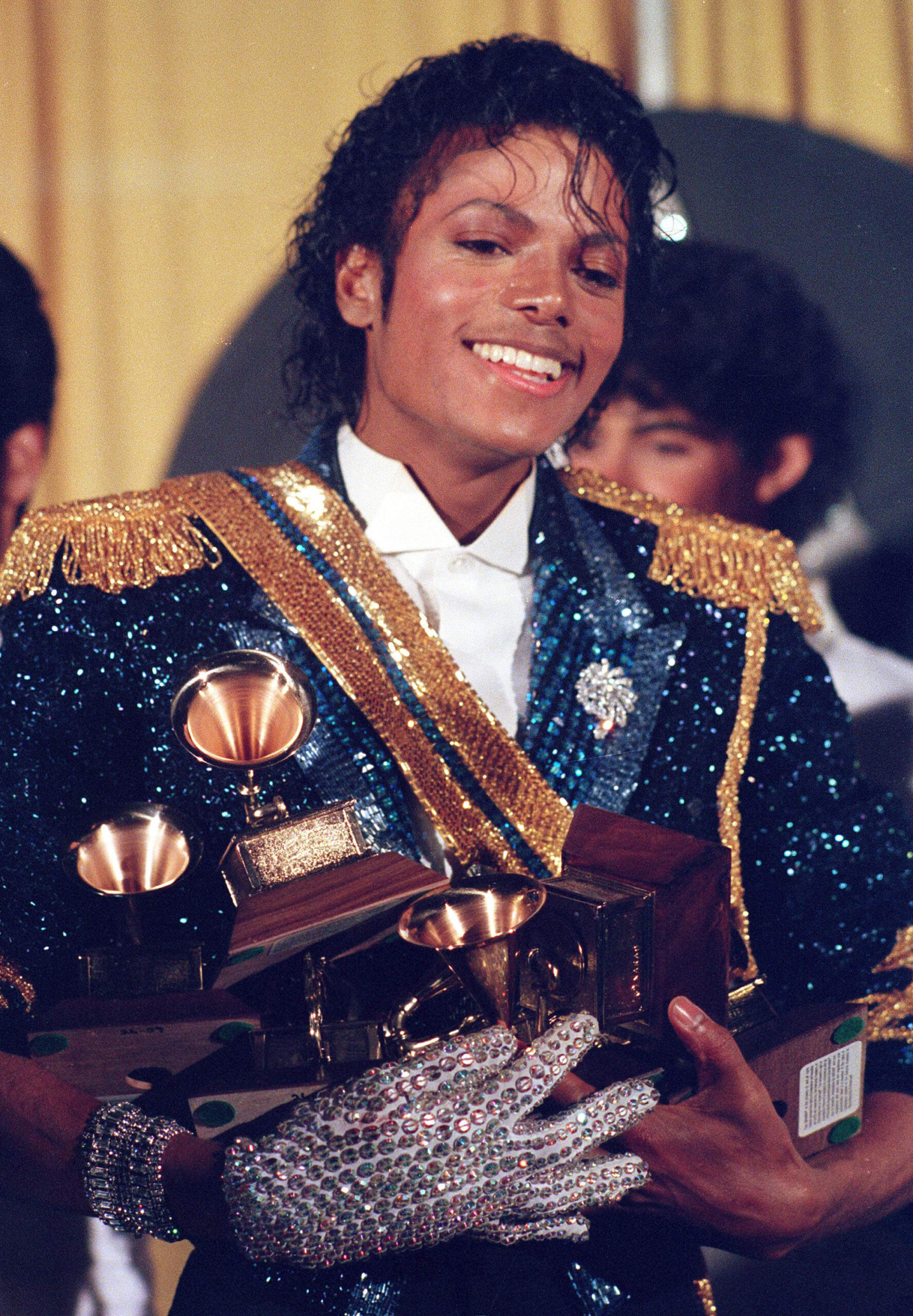 FILE - In this Feb. 28, 1984 file photo, Michael Jackson is seen backstage at the 26th annual Grammy Awards in Los Angeles as he poses with the awards he won in eight different categories. (AP Photo/Reed Saxon, file)