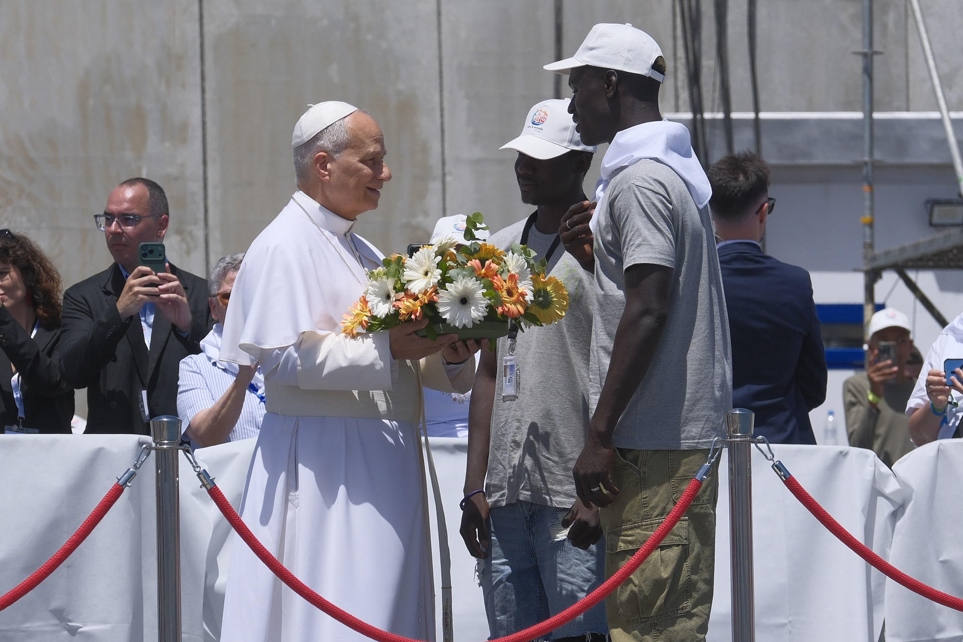 ARGUINEGUÍN (GRAN CANARIA), 11/06/2026.- El papa León XIV recibe flores de dos voluntarios para protagonizar una ofrenda floral en el mar en recuerdo de los migrantes muertos en la travesía durante el encuentro con más de un millar de inmigrantes de África, América Latina y con representantes de las principales instituciones y organizaciones sociales que trabajan en los servicios de rescate, acogida e integración en el muelle de Arguineguín, en la isla de Gran Canaria, este jueves, en el sexto día de su viaje a España. EFE/ Angel Medina G. POOL