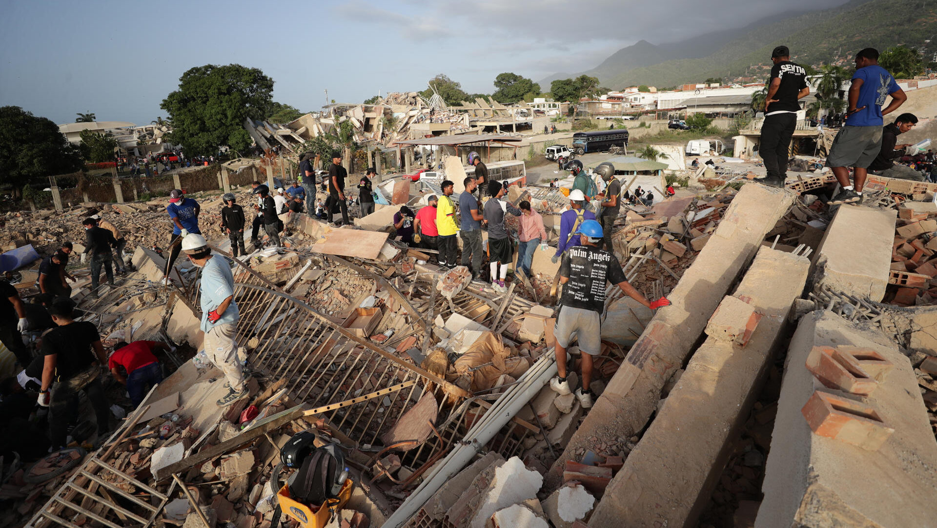 AME5030. LA GUAIRA (VENEZUELA), 26/06/2026.- Personas realizan labores de búsqueda en una zona afectada por un terremoto, este viernes en La Guaira (Venezuela). Venezuela afrontó su tercer día de emergencia con apoyo de brigadas de rescate de nueve países, entre ellos Estados Unidos y España, que se han sumado a las labores de búsqueda de supervivientes o fallecidos, tras el doble terremoto del pasado miércoles que deja al menos 920 muertos y 3.360 heridos, según cifras oficiales. EFE/ Ronald Peña R