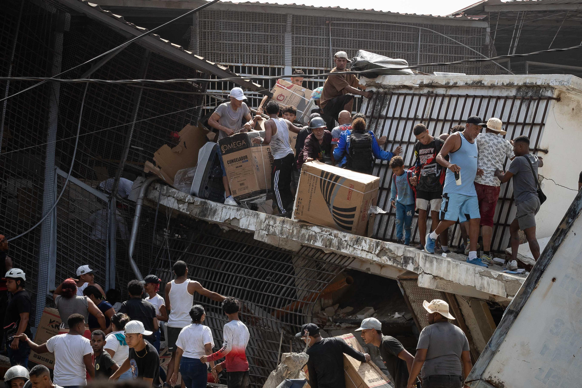 FOTODELDÍA AME4391. CATIA LA MAR (VENEZUELA), 25/06/2026.- Personas saquean un establecimiento comercial este jueves, en Catia La Mar (Venezuela). El número de fallecidos en Venezuela a causa de los dos terremotos del miércoles se elevó a 188 y el de heridos a 1.520, mientras que al menos 346 construcciones, entre edificios, hospitales y centros comerciales, resultaron afectadas, informó el presidente de la Asamblea Nacional (AN, Parlamento), el chavista Jorge Rodríguez. EFE/ Ronald Peña R.
