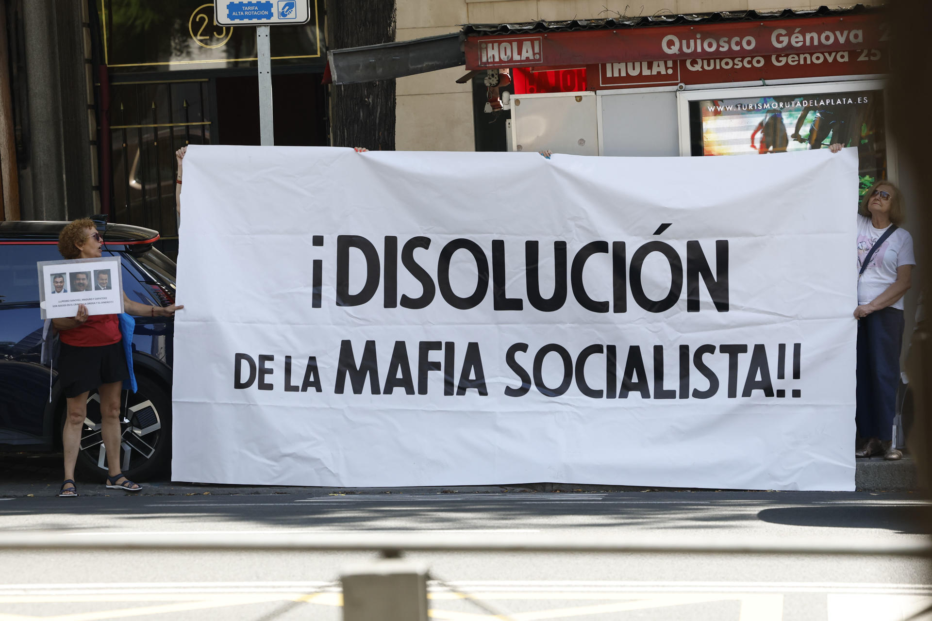 MADRID, 17/06/2026.- Dos mujeres sostienen un cartel contra el PSOE en las inmediaciones de la Audiencia Nacional, donde el expresidente del Gobierno, José Luis Rodríguez Zapatero, declara este miércoles como investigado por organización criminal, tráfico de influencias y falsedad en la causa sobre el préstamo a la compañía aérea Plus Ultra. EFE/ J.J.Guillen