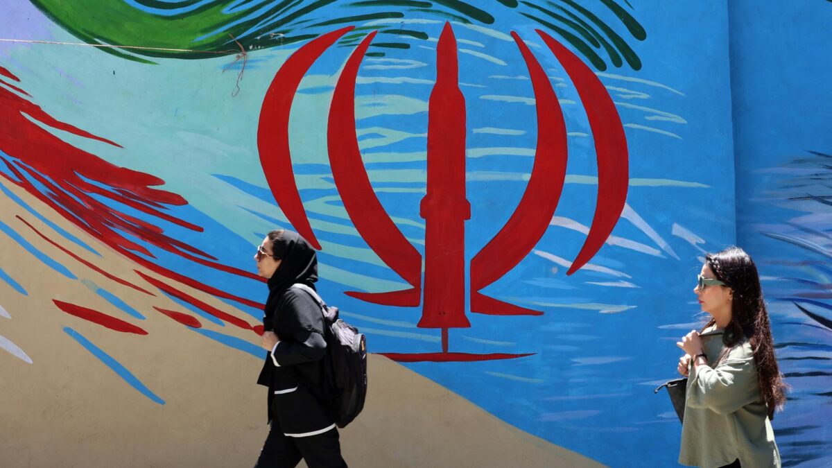 Ciudadanos iraníes pasan junto a un mural con la bandera nacional de Irán en una calle de Teherán, Irán, este lunes. El presidente estadounidense Donald Trump anunció en sus redes sociales que se ha alcanzado un acuerdo con Irán, el cual se firmará el 19 de junio en Suiza. (Suiza, Teherán) EFE/EPA/ABEDIN TAHERKENAREH RESTRICCIONES: Prohibido el acceso a medios de comunicación israelíes/canales de televisión en persa fuera de Irán/Prohibido el acceso a BBC Persian/VOA Persian/Manoto TV/Televisión Internacional de Irán. (Según lo dispuesto por la Dirección General de Medios de Comunicación Extranjeros de Irán)
