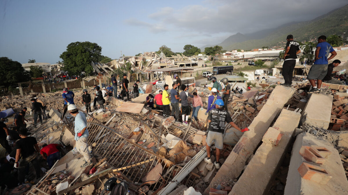 AME5030. LA GUAIRA (VENEZUELA), 26/06/2026.- Personas realizan labores de búsqueda en una zona afectada por un terremoto, este viernes en La Guaira (Venezuela). Venezuela afrontó su tercer día de emergencia con apoyo de brigadas de rescate de nueve países, entre ellos Estados Unidos y España, que se han sumado a las labores de búsqueda de supervivientes o fallecidos, tras el doble terremoto del pasado miércoles que deja al menos 920 muertos y 3.360 heridos, según cifras oficiales. EFE/ Ronald Peña R