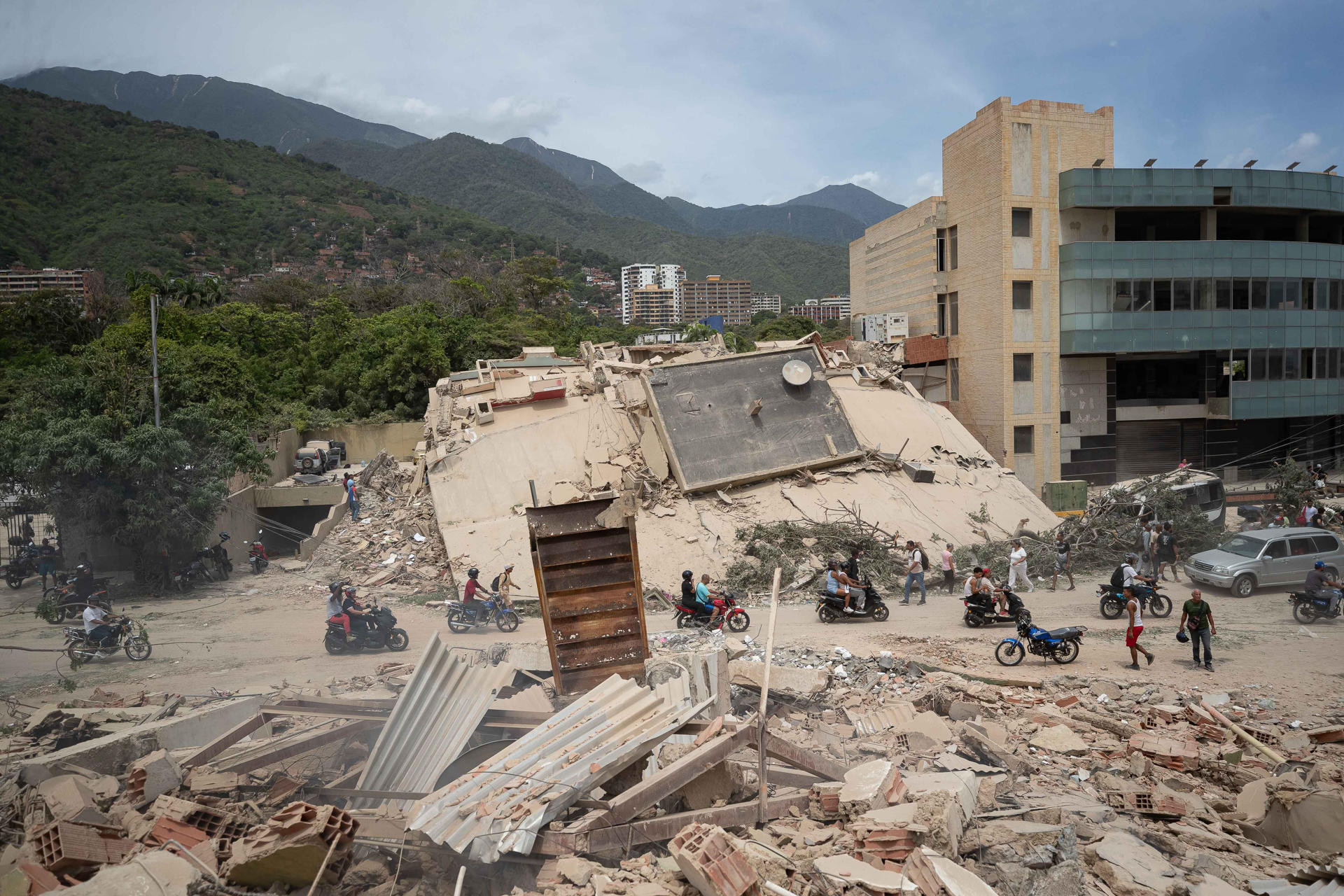 AME4355. LA GUAIRA (VENEZUELA), 25/06/2026.- Personas transitan frente a escombros de edificios afectados por terremotos este jueves, en La Guaira (Venezuela). El número de fallecidos en Venezuela a causa de los dos terremotos del miércoles se elevó a 188 y el de heridos a 1.520, mientras que al menos 346 construcciones, entre edificios, hospitales y centros comerciales, resultaron afectadas, informó el presidente de la Asamblea Nacional (AN, Parlamento), el chavista Jorge Rodríguez. EFE/ Ronald Peña R.