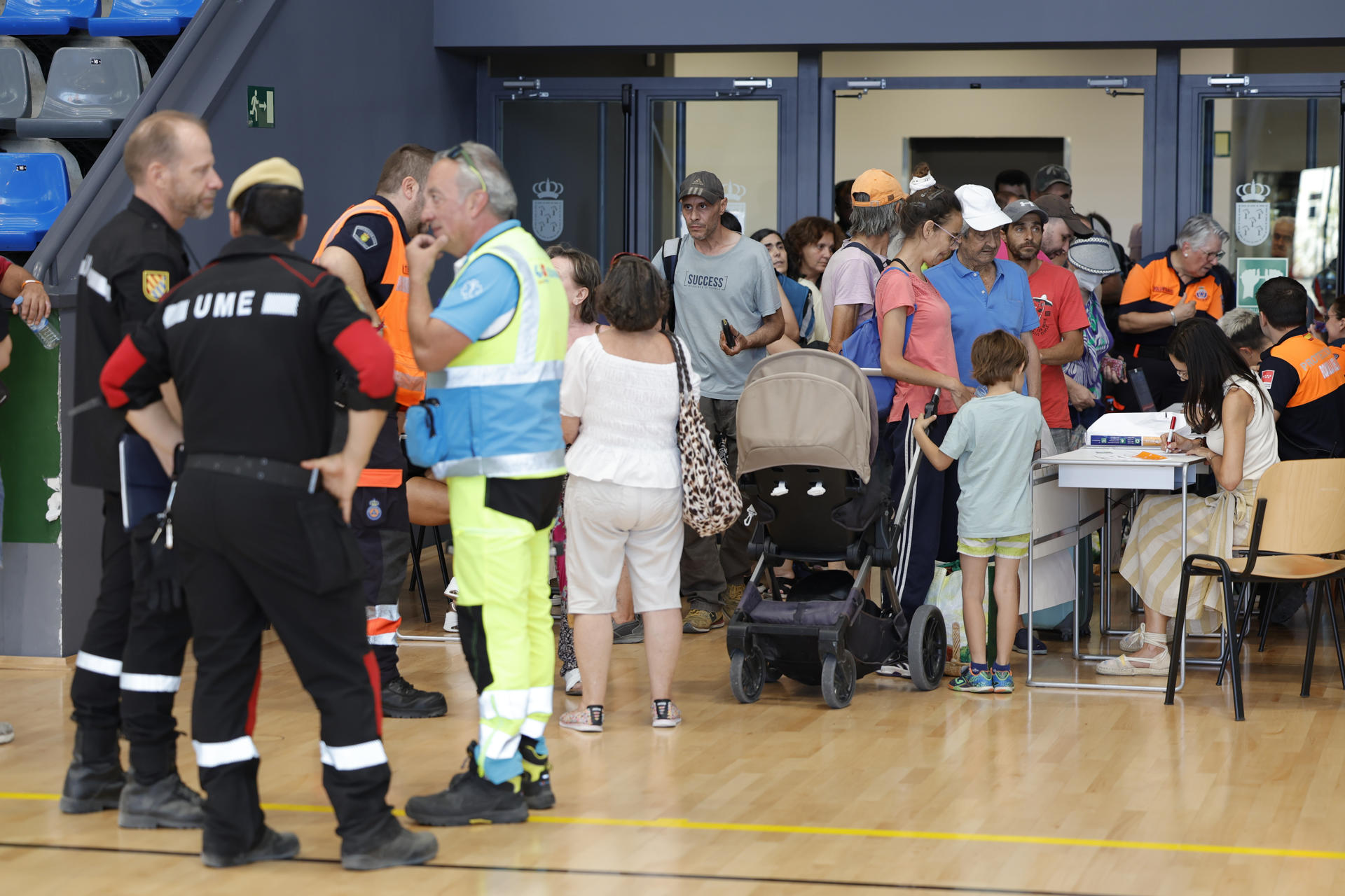 BOADILLA DEL MONTE (MADRID), 27/07/2026.- Decenas de personas evacuadas por el incendio de la sierra Oeste este lunes en el pabellón Felipe VI de Boadilla del Monte (Madrid). La Comunidad de Madrid mantiene activos 15 puntos de acogida para atender a las personas evacuadas por el incendio de la sierra Oeste, en los que ayer domingo se prestó asistencia a 2.468 personas. EFE/ Víctor Lerena