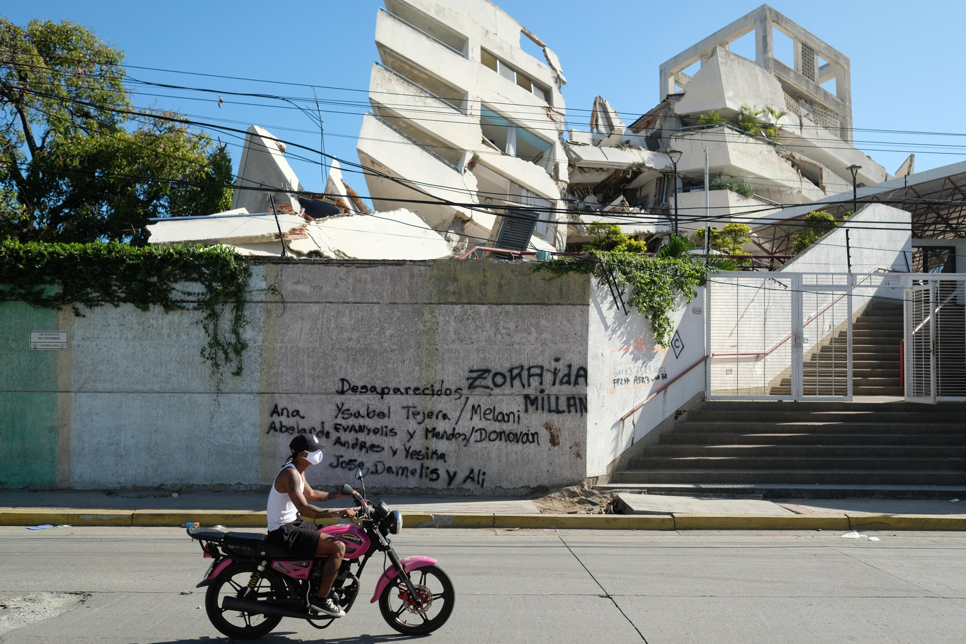 Una persona transita frente a un edificio colapsado con los nombres de personas desaparecidas durante el doble terremoto de magnitud 7,2 y 7,5 ocurrido el pasado 24 de Junio, este martes en La Guaira (Venezuela). EFE/ Xaume Olleros