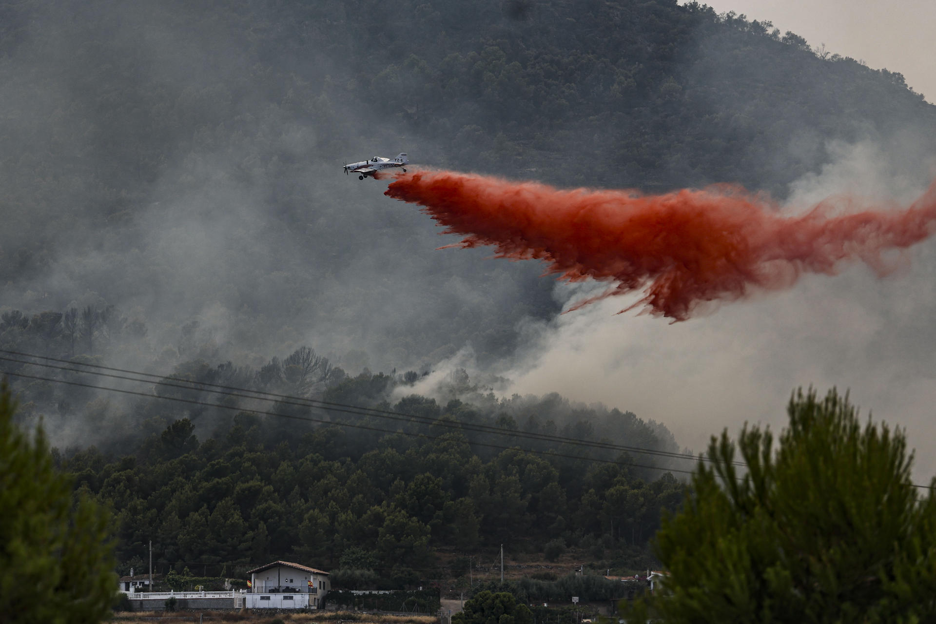 FOTODELDÍA GRAFCVA5189. BETXÍ (CASTELLÓN), 26/07/2026.- Un avión realiza una descarga con retardante en Betxí en el frente del incendio declarado este sábado en la Vall d'Uixó (Castellón), y que lleva quemadas ya unas 4.300 hectáreas y cuyo perímetro supera los 40 kilómetros. EFE/Manuel Bruque