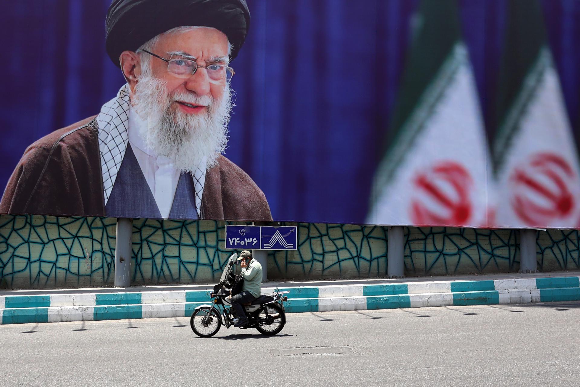 TEHRAN (IRAN(Islamic Republic Of)), 01/07/2026.- An Iranian man rides a motorbike past a large-scale poster of late Iranian Supreme Leader Ayatollah Ali Khamenei displayed along a highway, in Tehran, Iran, 01 July 2026. Iran is set to hold a multi-day state funeral from 04 to 09 July 2026 for late Iranian Supreme Leader Ayatollah Ali Khamenei, who was assassinated on 28 February. (Teherán) EFE/EPA/ABEDIN TAHERKENAREH -- RESTRICTIONS: NO Access Israel Media/Persian Language TV Stations Outside Iran/Strictly No Access BBC Persian/VOA Persian/Manoto TV/Iran International TV. (As mandated by Iran's Directorate General for Foreign Media) --