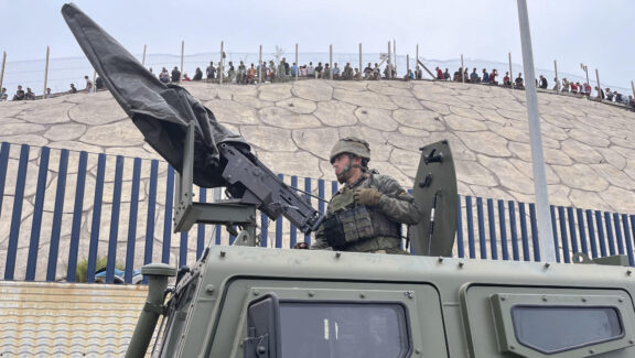 CEUTA (ESPAÑA), 31/07/2026.- El ejército desplegando en la frontera del Tarajal en Ceuta ante la atenta mirada de los inmigrantes este viernes, donde se han registrado violentos enfrentamientos en los perímetros fronterizos durante su intento de acceder desde Marruecos hacia Ceuta y Melilla. EFE/ Reduan Dris