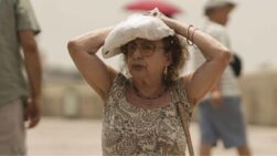 Un turista se protege del sol mientras cruza el Puente Romano de Córdoba.