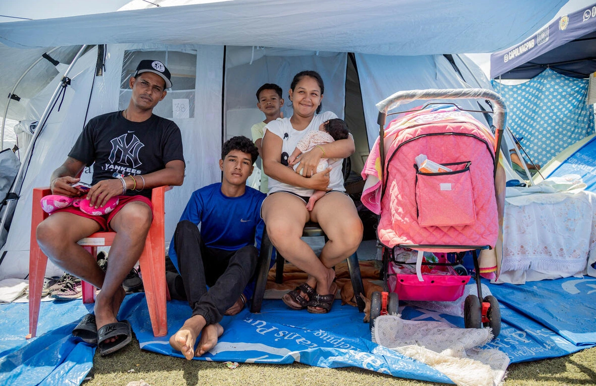 Gusmaira Rizo, de 30 años, sostiene a su hija recién nacida junto a su esposo y dos de sus hijos mayores en un campamento transitorio en César Nieves, La Guaira, Venezuela.