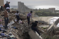 AME8590. CATIA LA MAR (VENEZUELA), 08/07/2026.- Integrantes de la Protección Civil de Venezuela buscan cuerpos entre los escombros de edificios destruidos por los terremotos en Venezuela, este miércoles, en Catia La Mar, La Guaira (Venezuela). La cifra de muertos por los terremotos de hace dos semanas subió a 3.811, mientras que la de heridos se mantuvo en 16.740, según el balance oficial. EFE/ Miguel Gutiérrez