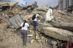 sacerdote Omar Pérez Gabino (d) caminando durante un recorrido para acompañar con oraciones a familiares, voluntarios y rescatistas que continúan las labores de recuperación de cuerpos atrapados bajo los escombros tras los terremotos del pasado 24 de junio en Venezuela. EFE/ Miguel Gutiérrez