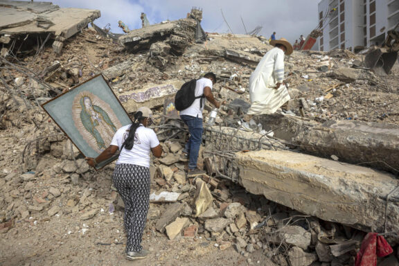 sacerdote Omar Pérez Gabino (d) caminando durante un recorrido para acompañar con oraciones a familiares, voluntarios y rescatistas que continúan las labores de recuperación de cuerpos atrapados bajo los escombros tras los terremotos del pasado 24 de junio en Venezuela. EFE/ Miguel Gutiérrez