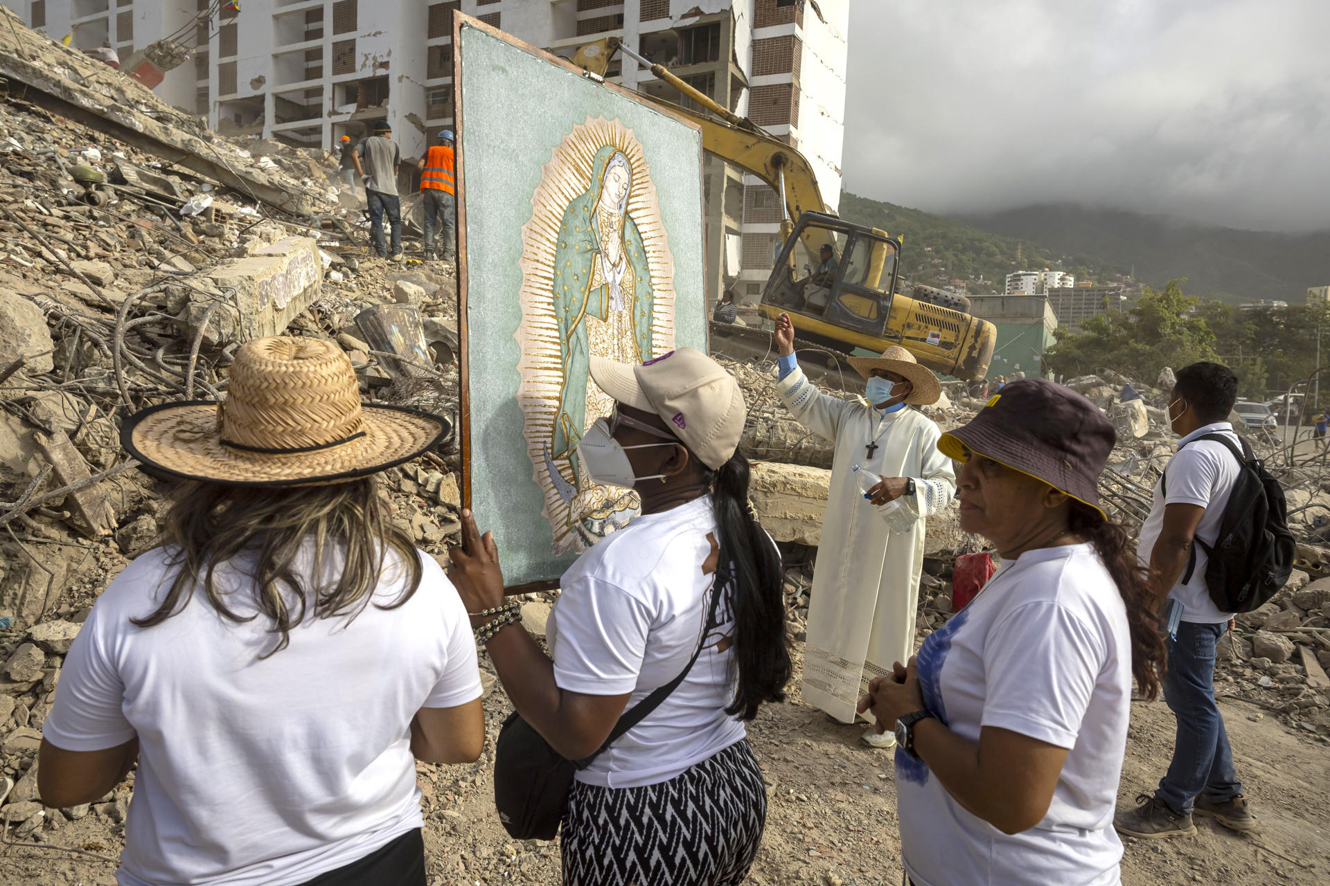 Fotografía del 17 de julio del 2026 que muestra al sacerdote Omar Pérez Gabino (atrás) durante un recorrido para acompañar con oraciones a familiares, voluntarios y rescatistas que continúan las labores de recuperación de cuerpos atrapados bajo los escombros tras los terremotos del pasado 24 de junio en Venezuela. EFE/ Miguel Gutiérrez
