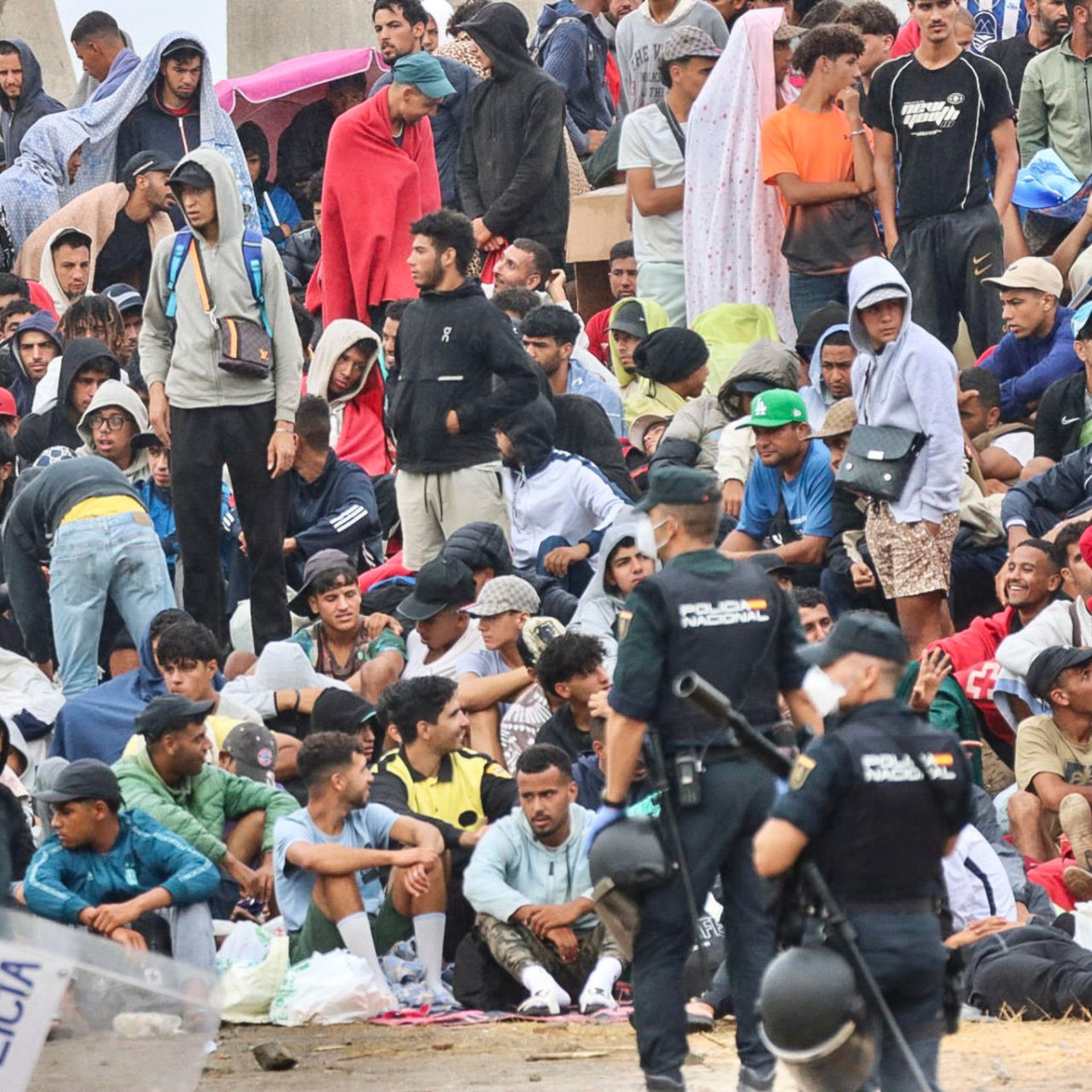 La policía vigila a inmigrantes que continúan viviendo en las inmediaciones de la playa del Trampolín en Ceuta, este viernes.