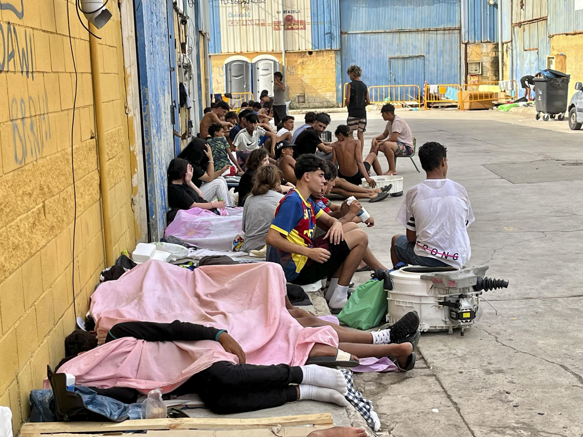 CEUTA, 03/08/2026.- Cientos de inmigrantes marroquíes descansan en las calles de Ceuta, este lunes. La vigilancia en el entorno de la frontera del Tarajal, tanto por vía marítima como terrestre, así como los nuevos medios de contención en la zona con la instalación de una barrera en el mar han reducido al mínimo las entradas a nado desde Marruecos. EFE/Reduan
