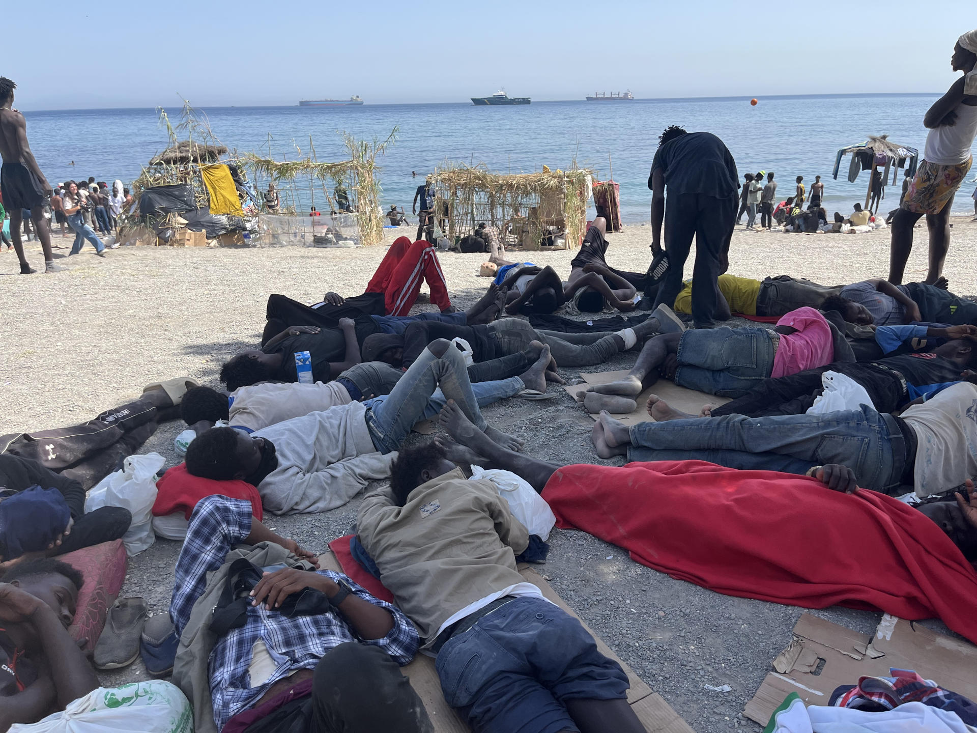 CEUTA, 09/08/2026.- Numerosos inmigrantes permanecen en la playa del Trampolín que se ha transformado en un asentamiento desde la entrada masiva registrada a finales de julio en la ciudad Ceuta. EFE/Reduan