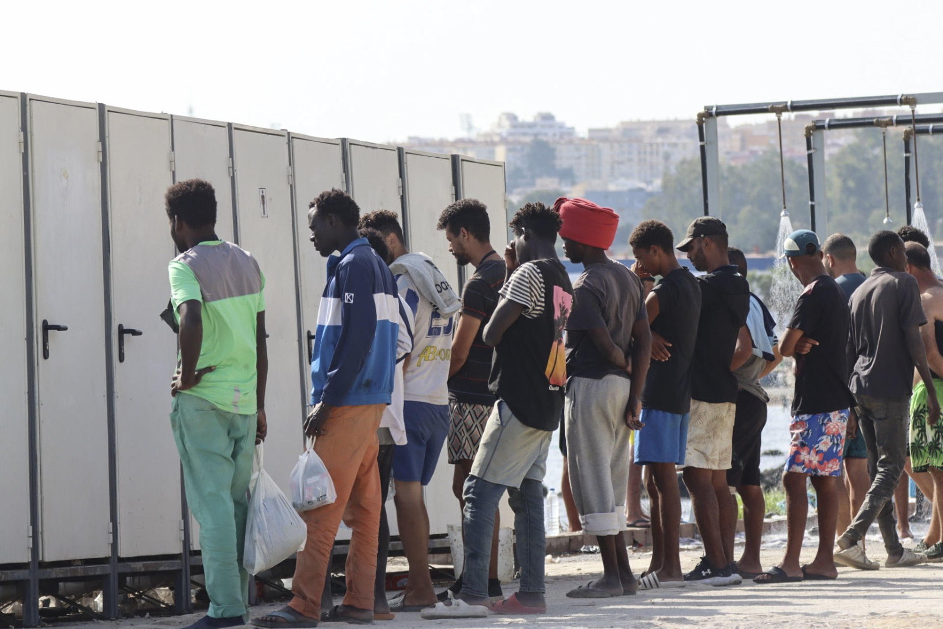CEUTA, 19/08/2026.- Miles de migrantes siguen viviendo en la playa del Trampolín y en otros lugares de Ceuta al aire libre mientras continúan los trabajos para instalar y acondicionar las carpas que en principio van a acoger a 1.500 personas. EFE/Reduan