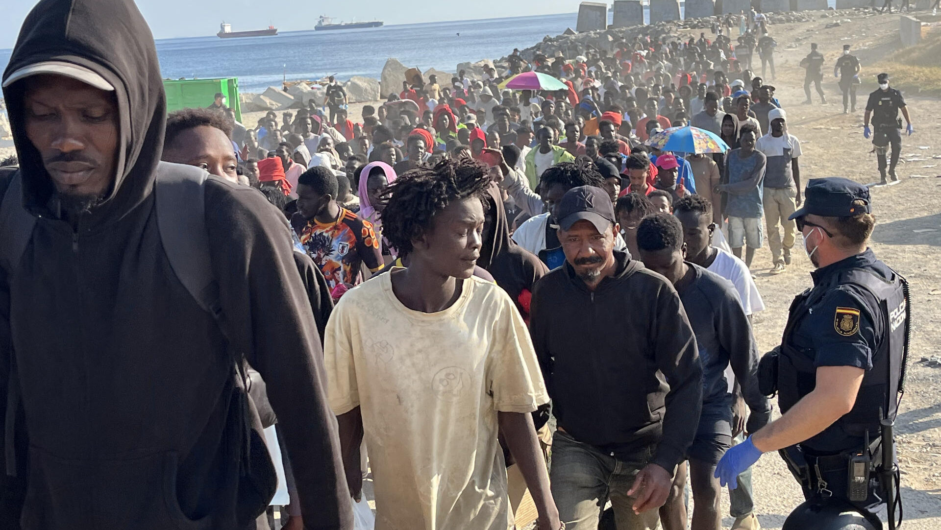 CEUTA, 20/08/2026.- Migrantes son desalojados de la playa del Trampolín en Ceuta tras habilitarse un espacio para su acogida este jueves. El Gobierno ha habilitado temporalmente varios espacios para la acogida de 1.800 personas migrantes que se encuentran en situación de calle en la playa del Trampolín y en la zona de Loma Colmenar, en Ceuta, que prevé ampliar progresivamente. EFE/Reduan