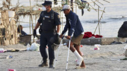 CEUTA, 20/08/2026.- Un policía acompaña a uno de los migrantes durante el desalojo de la playa del Trampolín en Ceuta este jueves. El Gobierno ha habilitado temporalmente varios espacios para la acogida de 1.800 personas migrantes que se encuentran en situación de calle en la playa del Trampolín y en la zona de Loma Colmenar, en Ceuta, que prevé ampliar progresivamente. EFE/Reduan