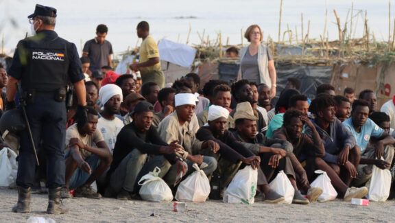 CEUTA, 20/08/2026.- Migrantes son desalojados de la playa del Trampolín en Ceuta tras habilitarse un espacio para su acogida este jueves. El Gobierno ha habilitado temporalmente varios espacios para la acogida de 1.800 personas migrantes que se encuentran en situación de calle en la playa del Trampolín y en la zona de Loma Colmenar, en Ceuta, que prevé ampliar progresivamente. EFE/Reduan