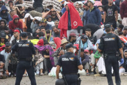 CEUTA, 21/08/2026.- La policía vigila a inmigrantes que continúan viviendo en las inmediaciones de la playa del Trampolín en Ceuta, este viernes. El secretario de Estado Juventud e Infancia, Rubén Pérez Correa, ha considerado "factible" llevar a cabo "en un plazo de pocas semanas" el traslado de 500 niñas migrantes no acompañadas desde Ceuta a la Península y, para ello, confía en la "voluntad" del Gobierno de la ciudad autónoma. EFE/Reduan