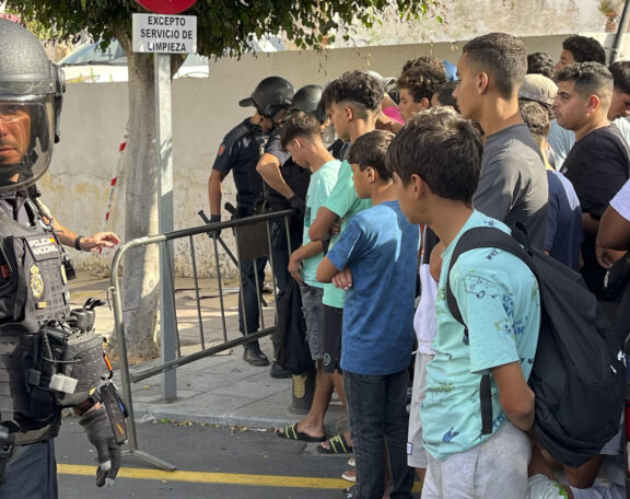 FOTODELDÍA CEUTA, 10/08/2026.-Multitud de menores migrantes esperan para su filiación frente a la Jefatura Superior de la Policía Nacional en Ceuta este lunes. La situación en Ceuta sigue lejos de normalizarse, con campamentos provisionales para muchos migrantes y miles de menores a la espera de una solución, y continúa marcando la disputa entre el Gobierno y el PP, que mantiene el pulso para que tres ministros comparezcan en el Senado aunque desde el Ejecutivo solo piensen hacerlo en el Congreso. -EFE/ Reduan