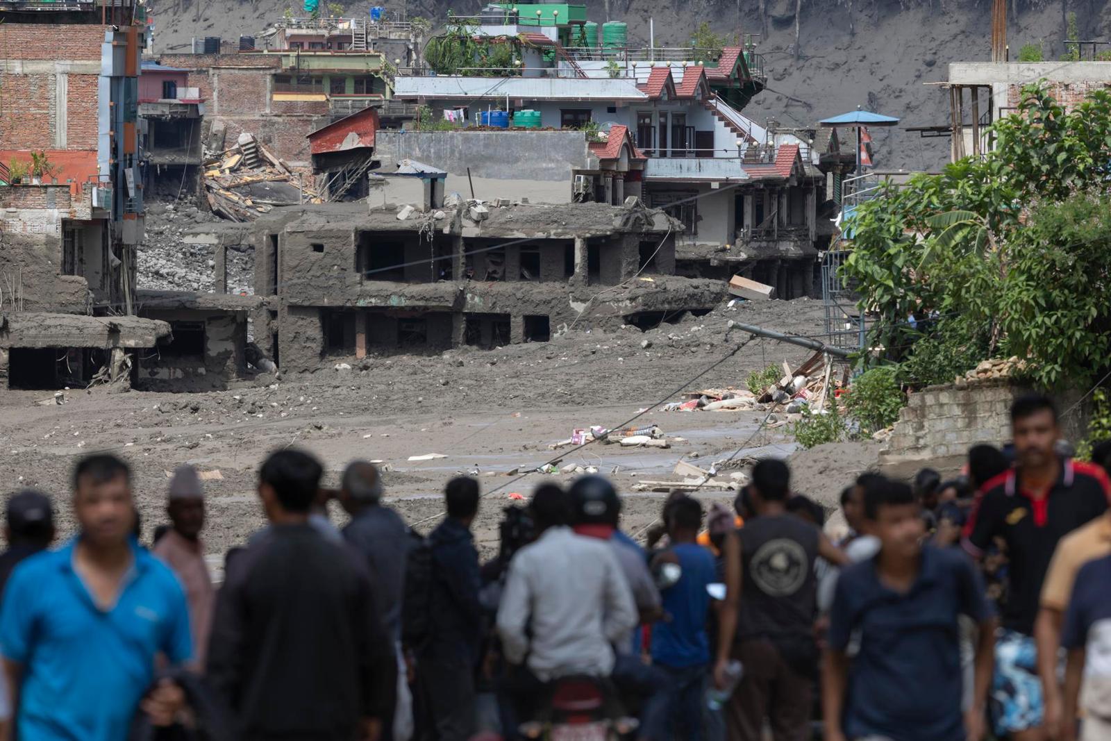 People watch as floodwaters sweep through Trishuli Bazar following a flash flood, in Nuwakot district, Nepal, 26 August 2026. Several people were killed and multiple others were reported missing after a massive flash flood swept through Rasuwa and Nuwakot districts causing widespread destruction to settlements and infrastructure, according to local authorities. (Inundaciones)