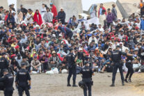 FOTODELDIA CEUTA, 21/08/2026.- La policía vigila a inmigrantes que continúan viviendo en las inmediaciones de la playa del Trampolín en Ceuta, este viernes. El secretario de Estado Juventud e Infancia, Rubén Pérez Correa, ha considerado "factible" llevar a cabo "en un plazo de pocas semanas" el traslado de 500 niñas migrantes no acompañadas desde Ceuta a la Península y, para ello, confía en la "voluntad" del Gobierno de la ciudad autónoma. EFE/Reduan