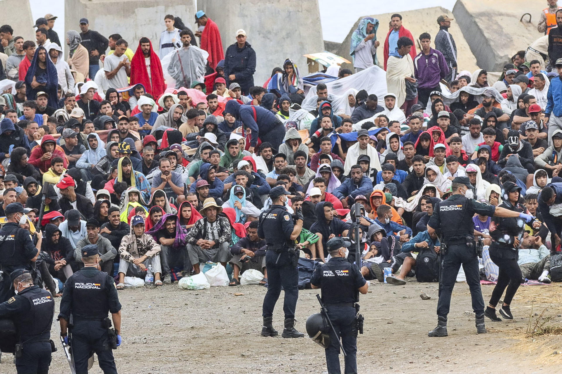 FOTODELDIA CEUTA, 21/08/2026.- La policía vigila a inmigrantes que continúan viviendo en las inmediaciones de la playa del Trampolín en Ceuta, este viernes. El secretario de Estado Juventud e Infancia, Rubén Pérez Correa, ha considerado "factible" llevar a cabo "en un plazo de pocas semanas" el traslado de 500 niñas migrantes no acompañadas desde Ceuta a la Península y, para ello, confía en la "voluntad" del Gobierno de la ciudad autónoma. EFE/Reduan