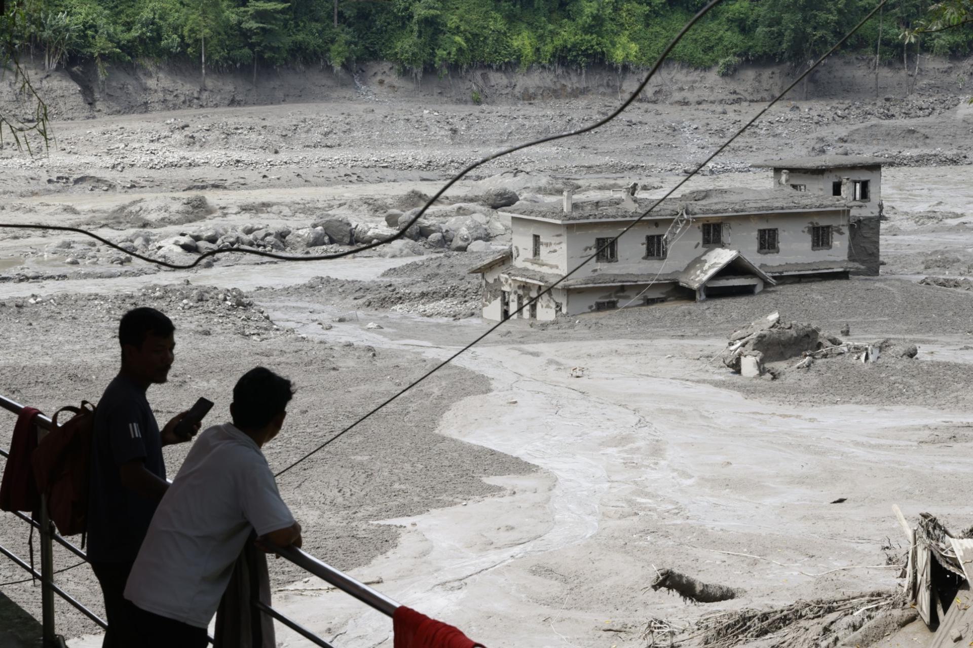 Trishuli Bazar (Nepal), 26/08/2026.- People watch floodwaters sweeping through Trishuli Bazar following a flash flood, in Nuwakot district, Nepal, 26 August 2026. Several people were killed and multiple others were reported missing after a massive flash flood swept through Rasuwa and Nuwakot districts causing widespread destruction to settlements and infrastructure, according to local authorities. (Inundaciones) EFE/EPA/NARENDRA SHRESTHA