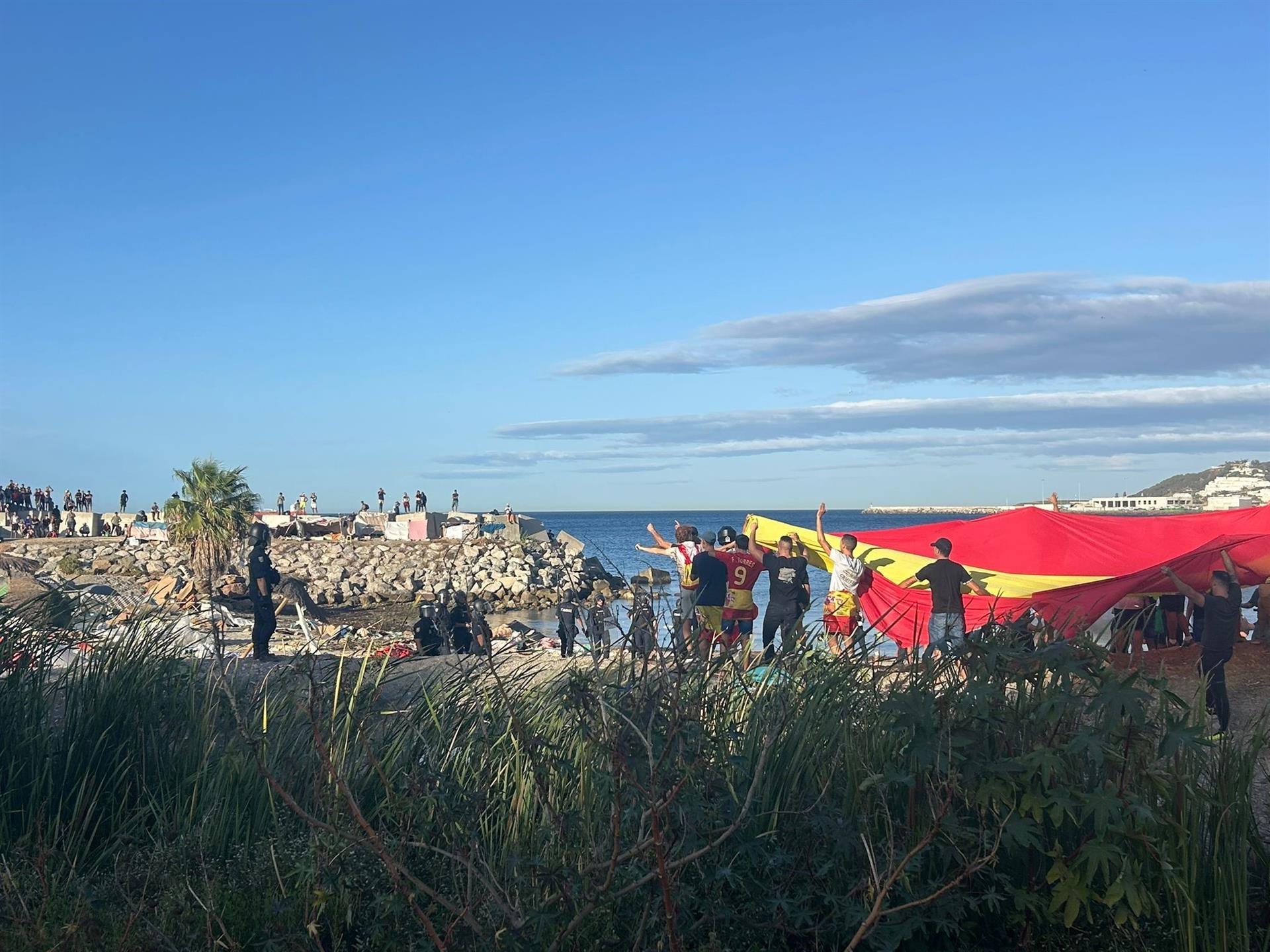 Manifestantes con una bandera gigante de España en una playa de Ceuta - EUROPA PRESS GABRIELA SARDÁ
