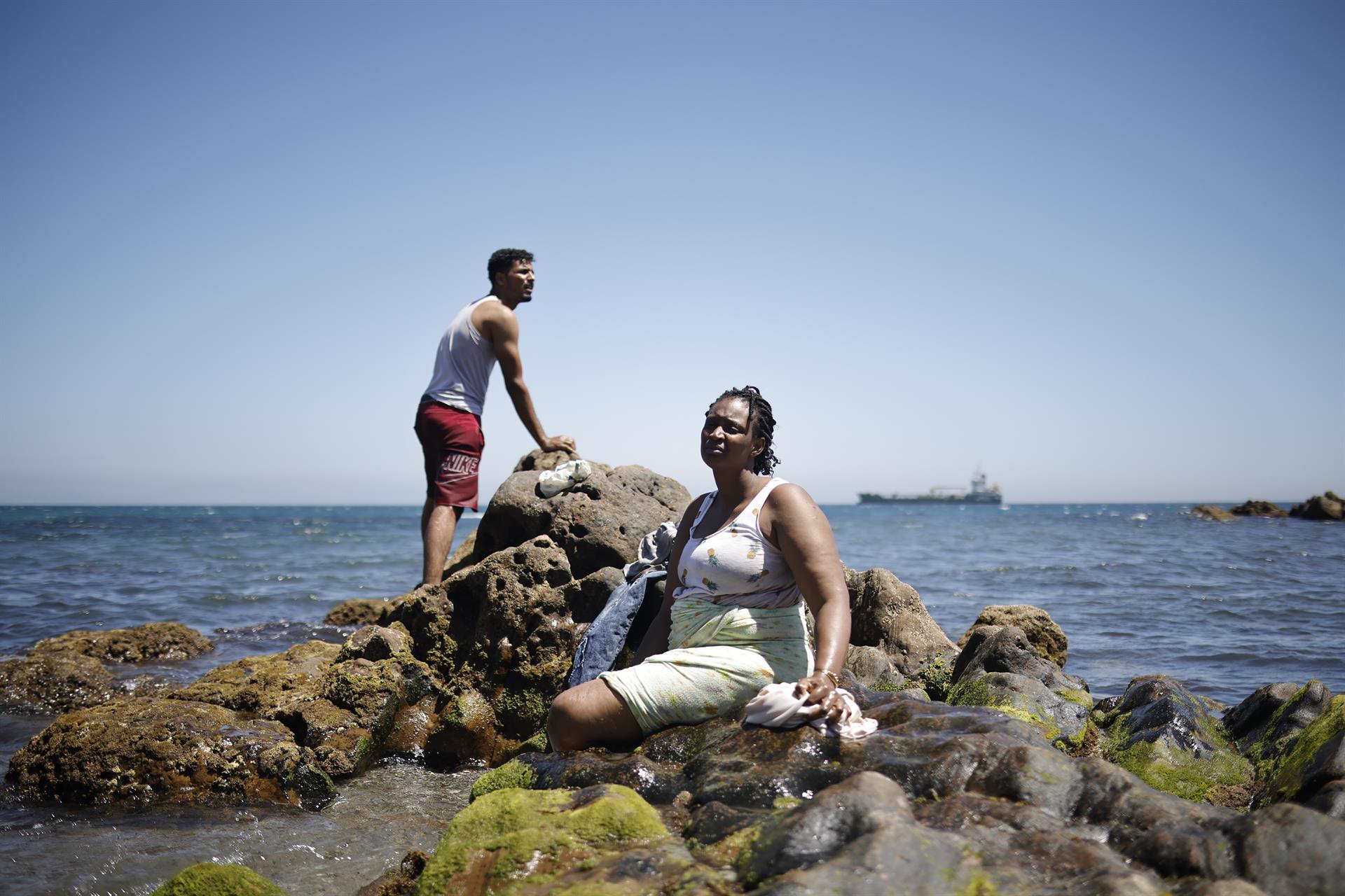 Un hombre y una mujer migrante en la playa, a 2 de agosto de 2026, en Ceuta (España). - Jesús Torres - Europa Press