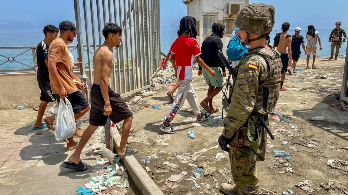 Un militar español observa como varios inmigrantes cruzan la frontera para volver a Marruecos,