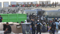 CEUTA, 20/08/2026.- Migrantes son desalojados de la playa del Trampolín en Ceuta tras habilitarse un espacio para su acogida este jueves. El Gobierno ha habilitado temporalmente varios espacios para la acogida de 1.800 personas migrantes que se encuentran en situación de calle en la playa del Trampolín y en la zona de Loma Colmenar, en Ceuta, que prevé ampliar progresivamente. EFE/Reduan