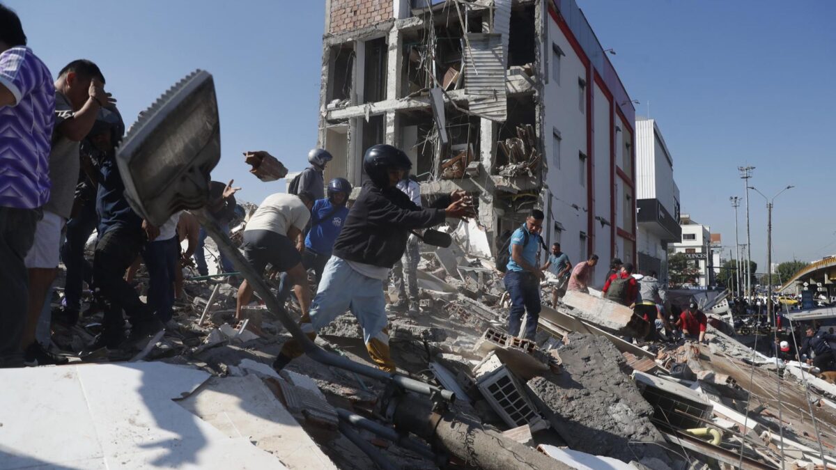 Varias personas caminan sobre los escombros de un edificio colapsado en Cali.