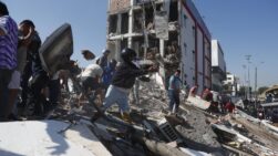 Varias personas caminan sobre los escombros de un edificio colapsado en Cali.