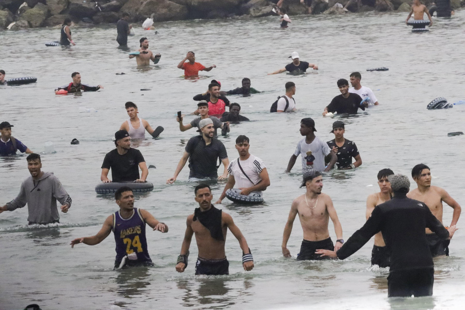 CEUTA (ESPAÑA), 31/07/2026.- Un grupo de inmigrantes en la playa junto al paso fronterizo del Tarajal en Ceuta este viernes, donde se han registrado violentos enfrentamientos en los perímetros fronterizos durante su intento de acceder desde Marruecos hacia Ceuta y Melilla. EFE/ Reduan Dris